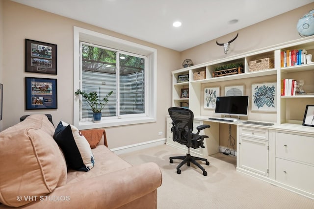 home office with built in desk and light carpet