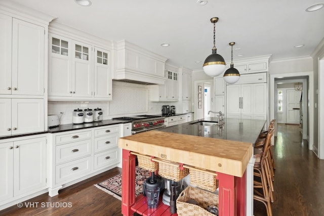 kitchen with decorative light fixtures, white cabinetry, sink, custom exhaust hood, and high end appliances