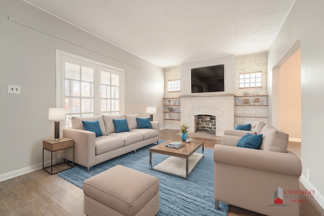 living room featuring wood-type flooring and a brick fireplace