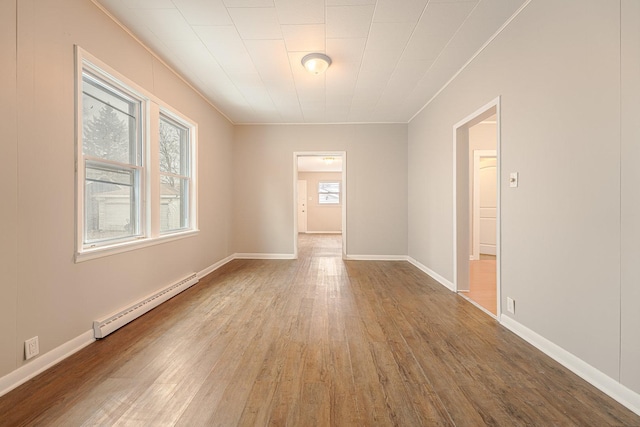 empty room with baseboard heating and hardwood / wood-style flooring