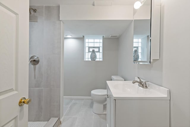 bathroom with vanity, tiled shower, and toilet