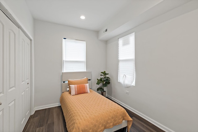 bedroom with multiple windows, dark hardwood / wood-style flooring, and a closet