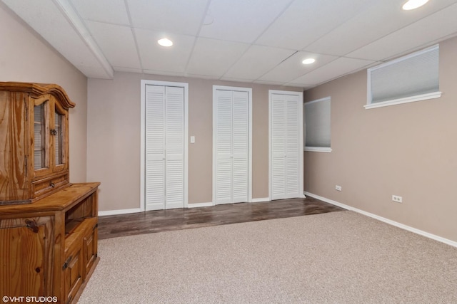 unfurnished bedroom featuring a paneled ceiling, carpet floors, and two closets