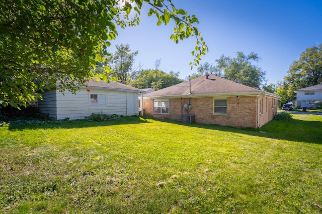 back of property with central AC unit and a lawn