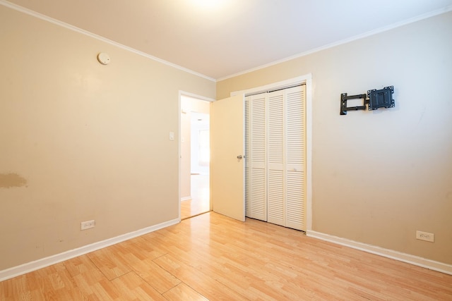 unfurnished bedroom featuring light hardwood / wood-style flooring, ornamental molding, and a closet