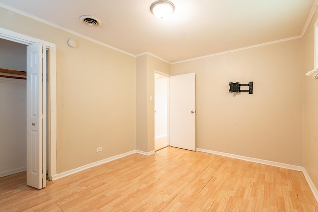 unfurnished bedroom with ornamental molding, a closet, and light wood-type flooring