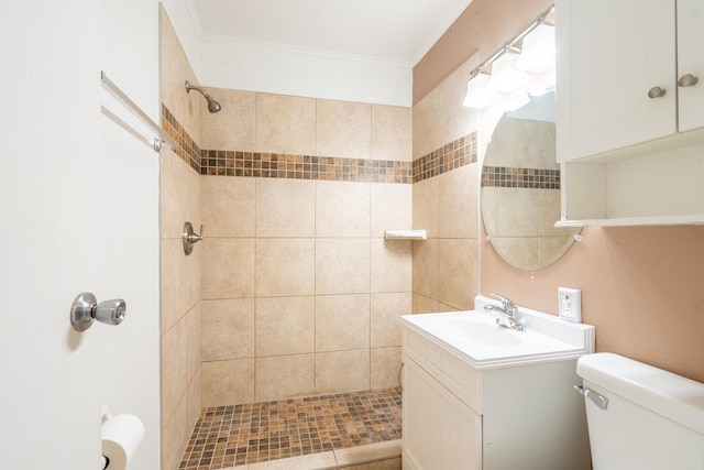 bathroom with vanity, tiled shower, ornamental molding, and toilet