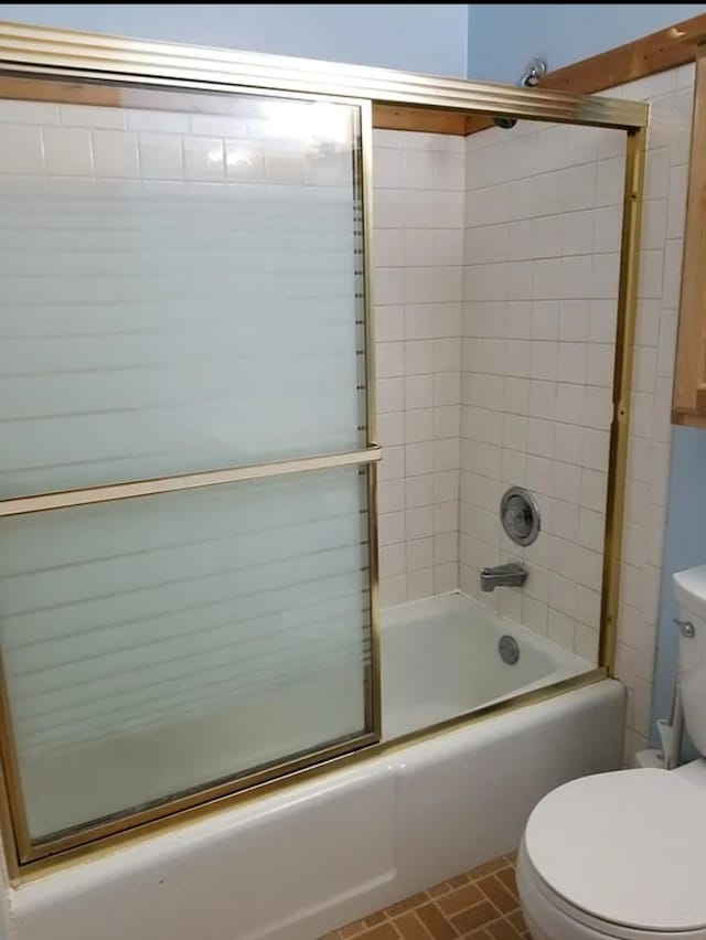 bathroom featuring toilet and combined bath / shower with glass door