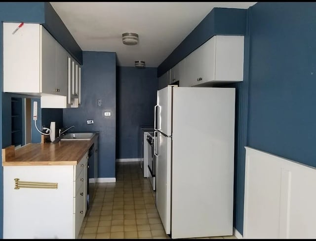 kitchen with light tile patterned flooring, dishwasher, sink, white cabinets, and white fridge