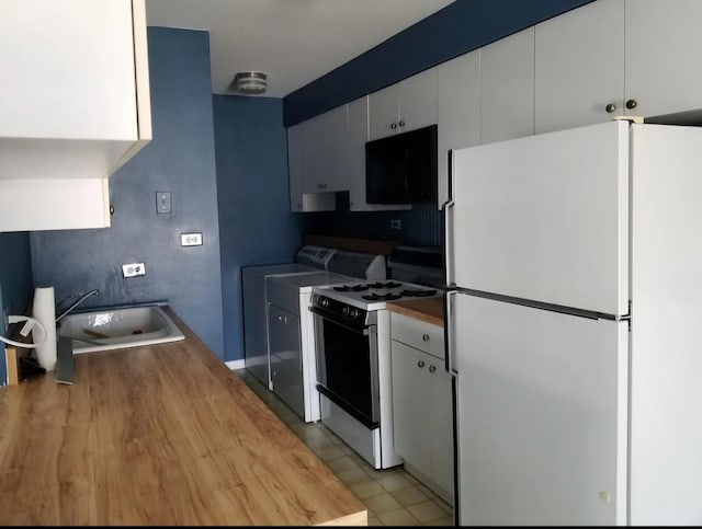 kitchen featuring sink, gas stove, white fridge, and white cabinets