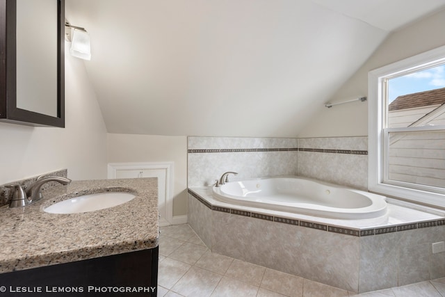 bathroom featuring a relaxing tiled tub, vanity, vaulted ceiling, and tile patterned floors