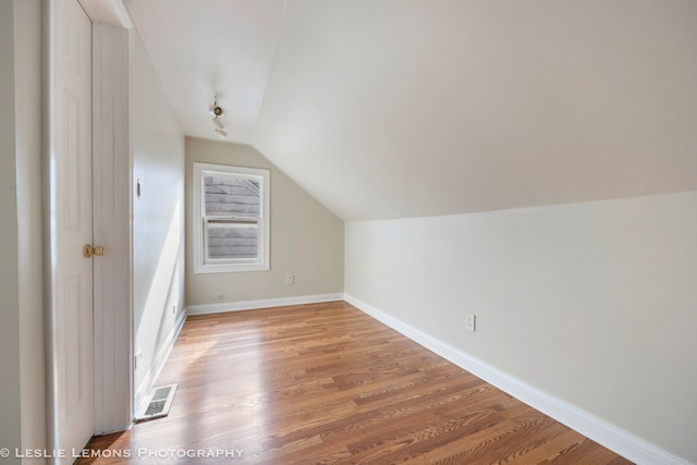 additional living space with wood-type flooring and vaulted ceiling