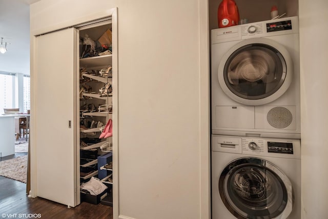 laundry room with dark hardwood / wood-style flooring and stacked washer and dryer