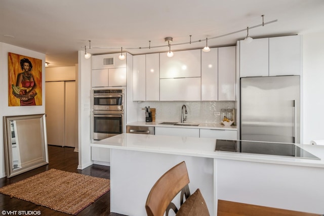 kitchen featuring white cabinetry, appliances with stainless steel finishes, sink, and decorative light fixtures