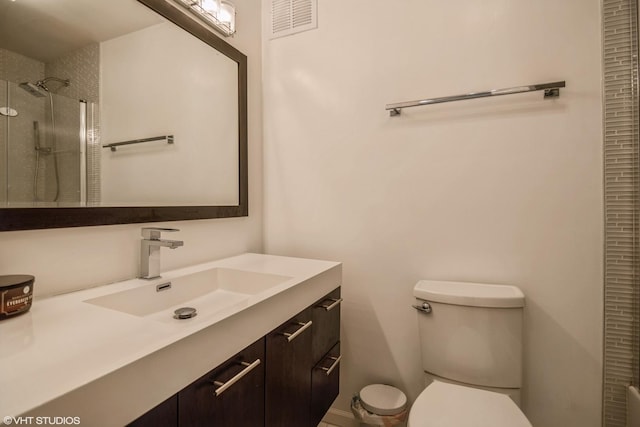 bathroom featuring vanity, toilet, and a tile shower