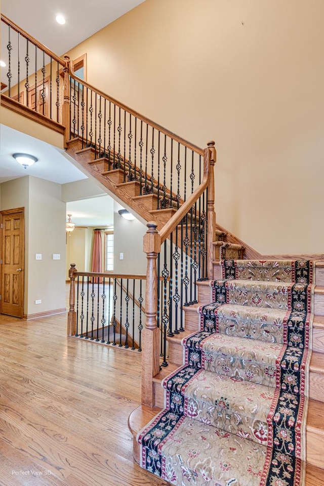 staircase with hardwood / wood-style flooring and a towering ceiling