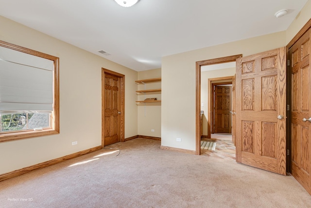 unfurnished bedroom featuring a walk in closet and light colored carpet