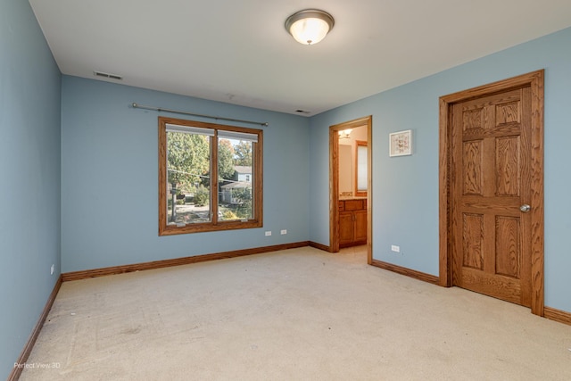 unfurnished bedroom featuring ensuite bath and light colored carpet