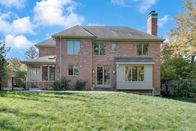 rear view of house featuring a sunroom and a lawn