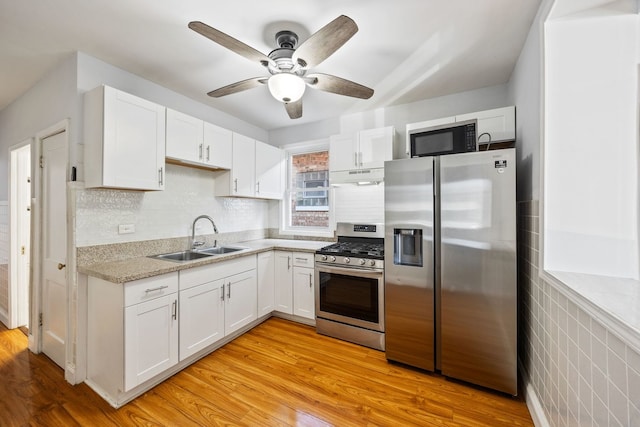 kitchen with appliances with stainless steel finishes, sink, white cabinets, ceiling fan, and light hardwood / wood-style floors