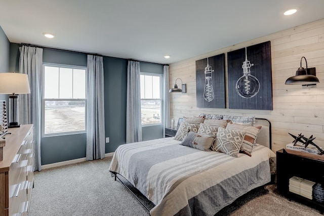 bedroom with light carpet and wooden walls