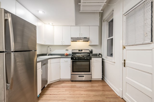 kitchen featuring stainless steel appliances, dark countertops, white cabinetry, a sink, and under cabinet range hood