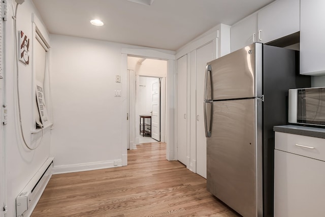 kitchen with light wood-style floors, a baseboard radiator, white cabinets, and freestanding refrigerator