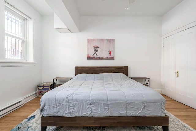 bedroom featuring a baseboard heating unit and wood finished floors