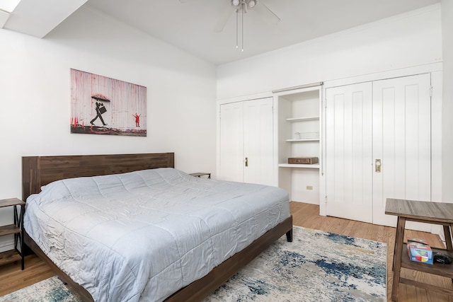 bedroom featuring two closets, ceiling fan, and wood finished floors