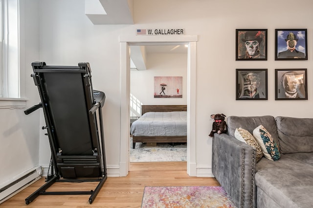 interior space with a baseboard heating unit, wood finished floors, and baseboards