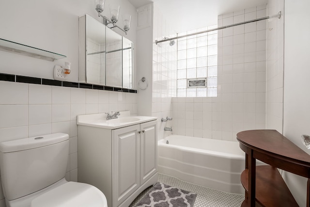 bathroom featuring toilet, vanity, tile walls, tub / shower combination, and tile patterned floors