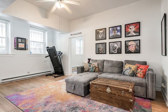 living area with baseboard heating, wood finished floors, and a ceiling fan