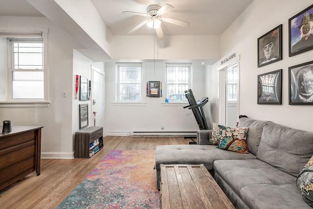 living area with a baseboard heating unit, baseboards, light wood finished floors, and a ceiling fan