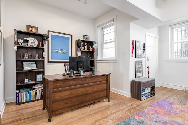 home office with light wood-style flooring and baseboards