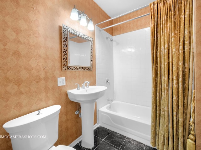 bathroom featuring toilet, a sink, shower / tub combo, tile patterned flooring, and baseboards