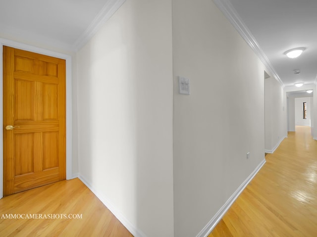 hallway featuring light wood-style flooring, baseboards, and ornamental molding