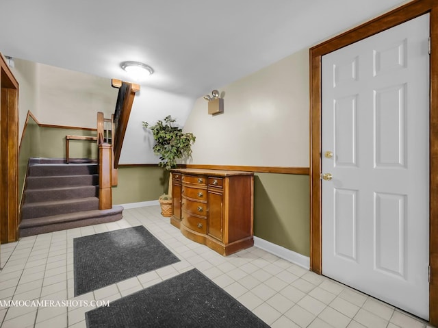 foyer entrance with stairs, light tile patterned flooring, and baseboards