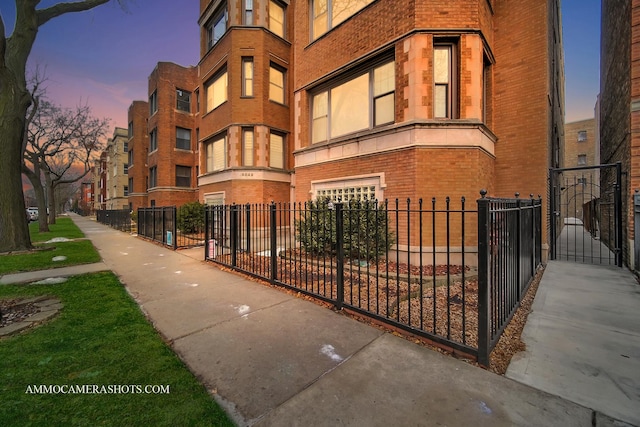 property at dusk with a fenced front yard and a garage