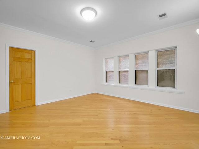 unfurnished room with light wood finished floors, visible vents, baseboards, and ornamental molding