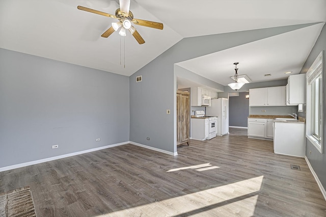 kitchen featuring sink, vaulted ceiling, hardwood / wood-style flooring, white appliances, and white cabinets