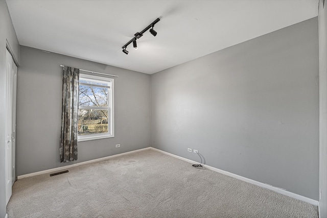 carpeted empty room featuring rail lighting