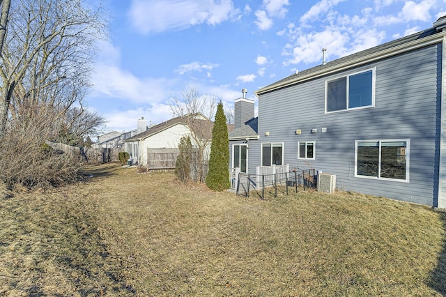 rear view of property featuring cooling unit and a lawn