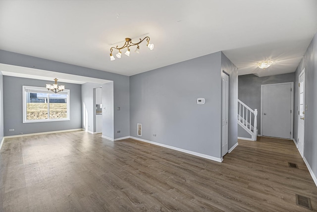 unfurnished living room with dark wood-type flooring and a notable chandelier