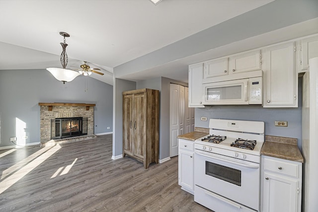 kitchen featuring white cabinetry, white appliances, ceiling fan, a brick fireplace, and light wood-type flooring