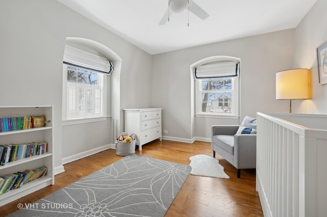 interior space with multiple windows, wood finished floors, baseboards, and ceiling fan