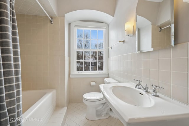 bathroom featuring toilet, tile walls, shower / tub combo, and tile patterned flooring