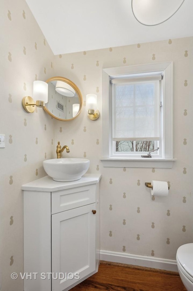 bathroom featuring baseboards, toilet, wood finished floors, and vanity