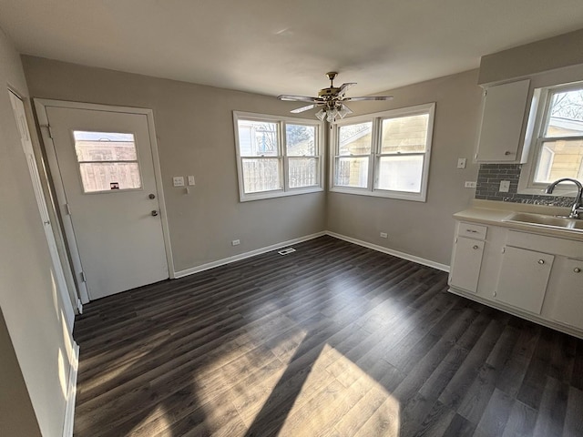 unfurnished dining area with ceiling fan, sink, and dark hardwood / wood-style floors