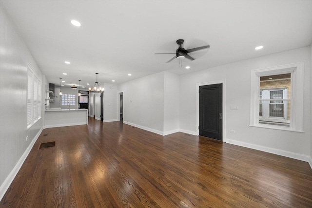 unfurnished living room with recessed lighting, visible vents, dark wood finished floors, and ceiling fan with notable chandelier