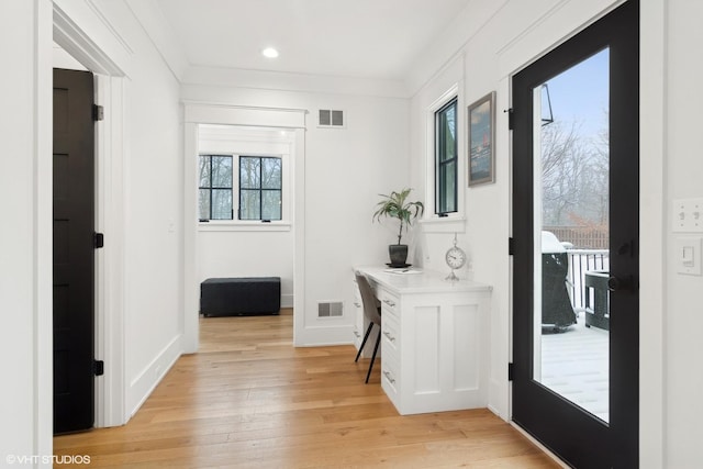 doorway with crown molding and light hardwood / wood-style floors